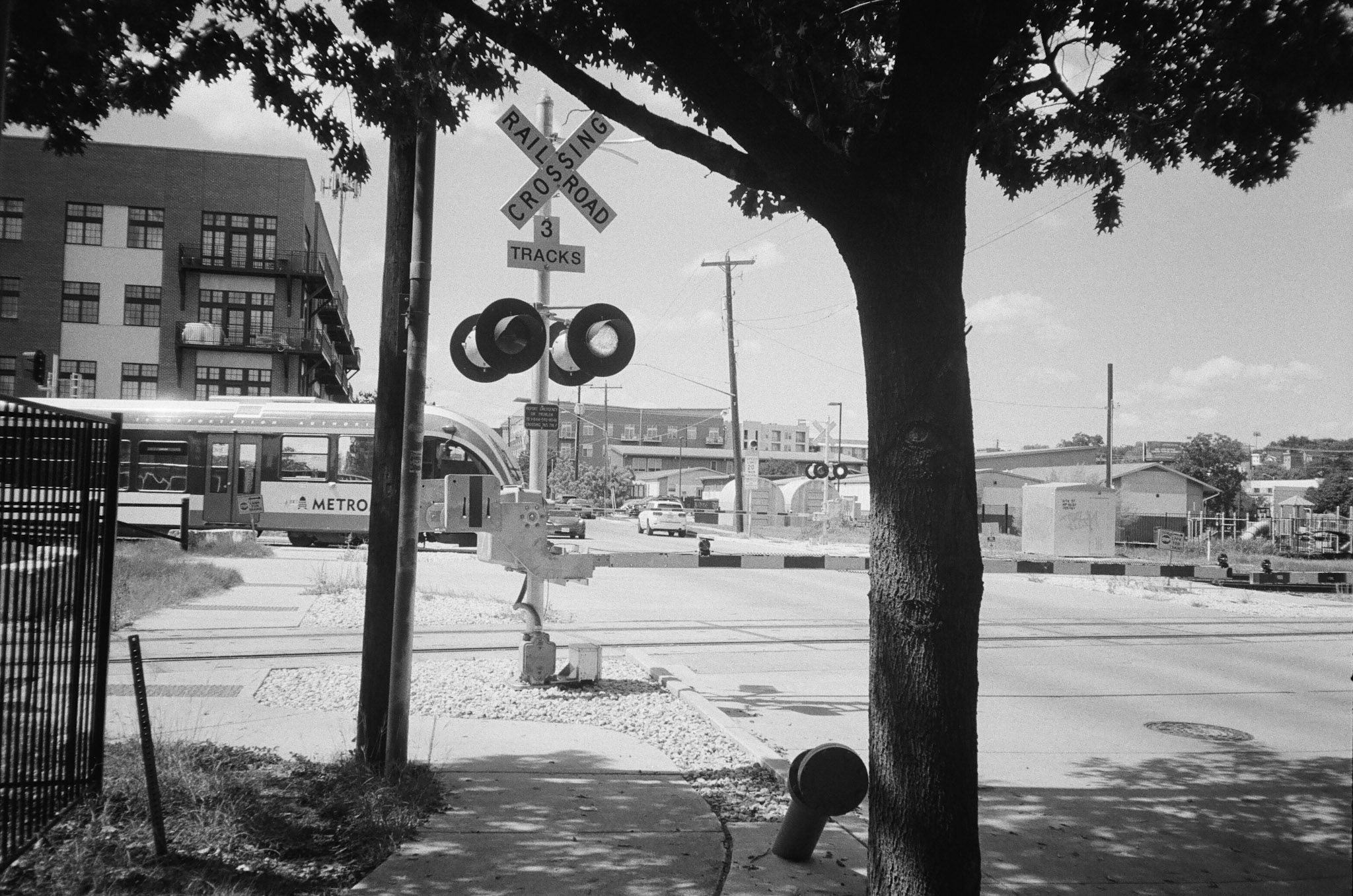 An Austin, TX Metro train crossing. The train is just entering the intersection with the gates down.