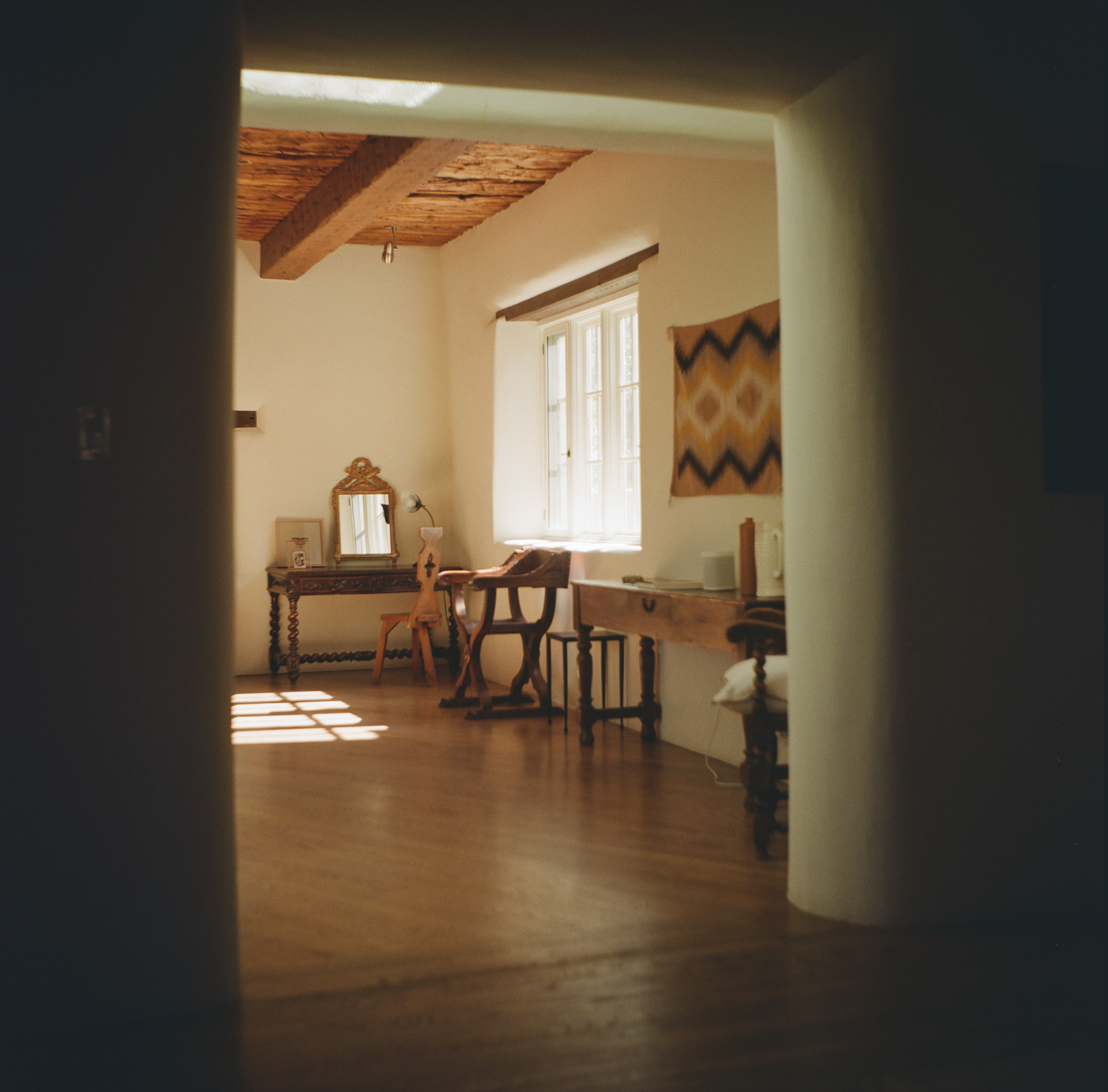 A well-lit room with lots of wood furniture in a pueblo style home.