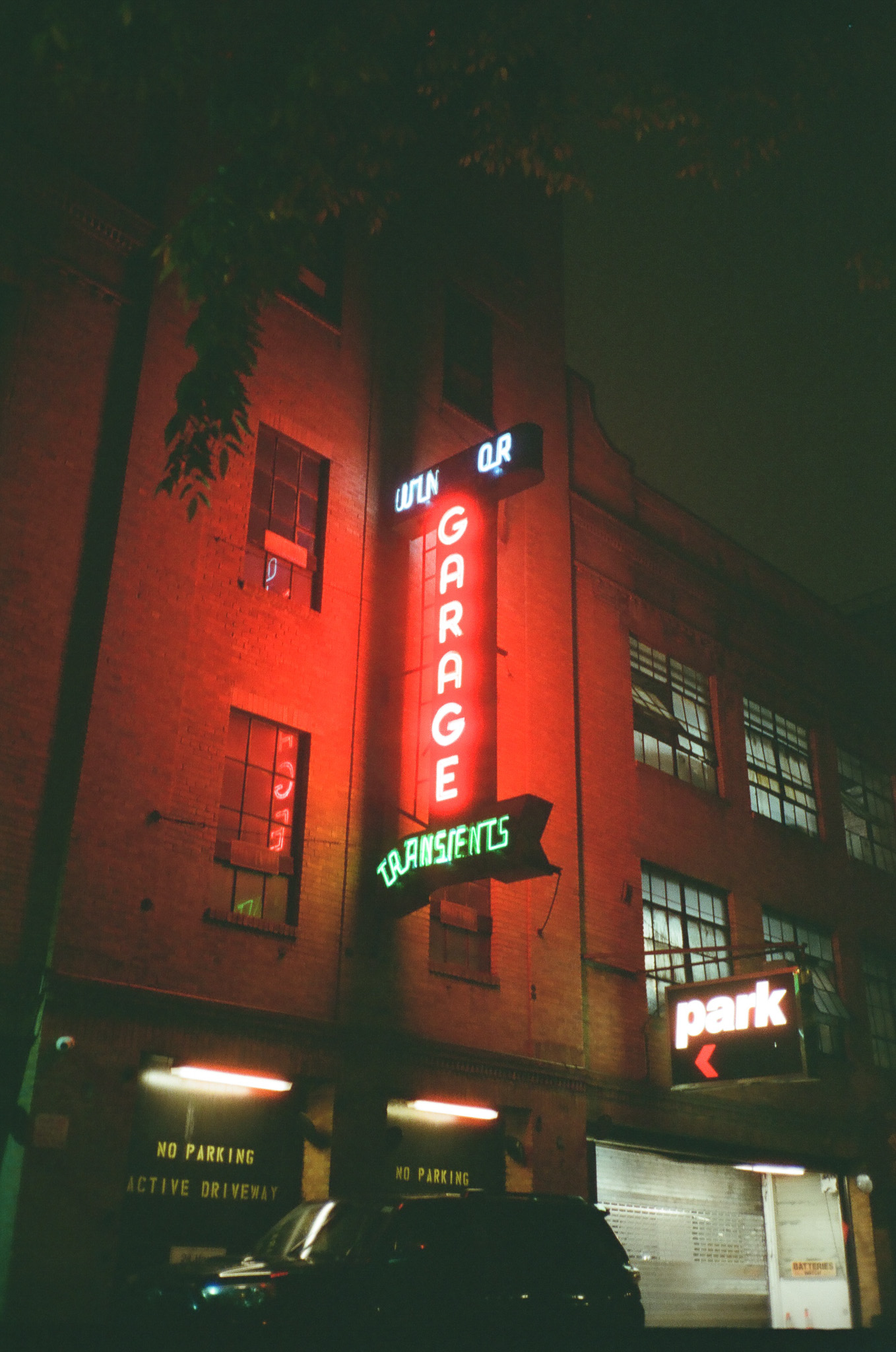 A neon garage sign attached to a brick building at night.