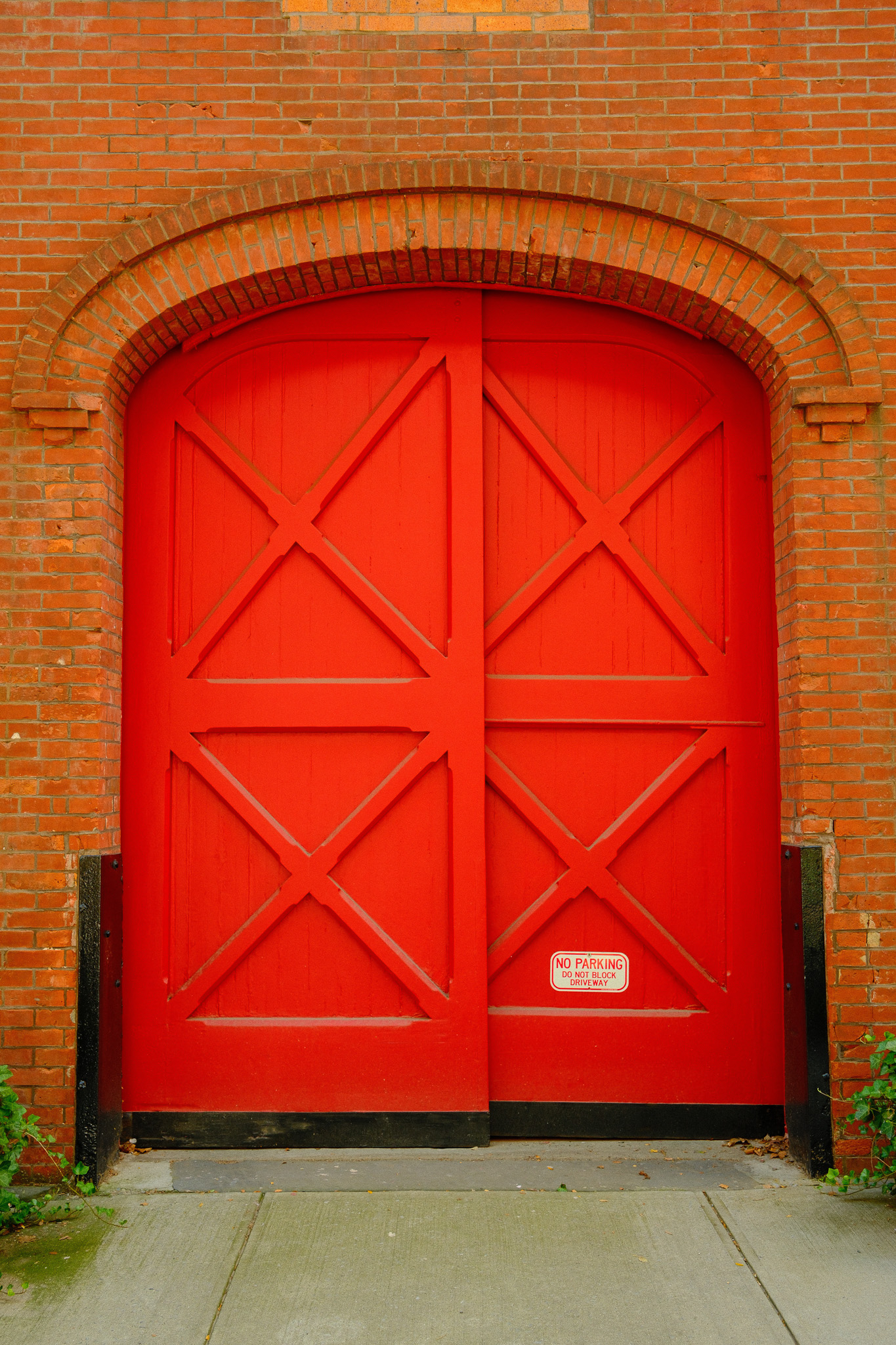 A large wooden red carriage door in a brick wall.