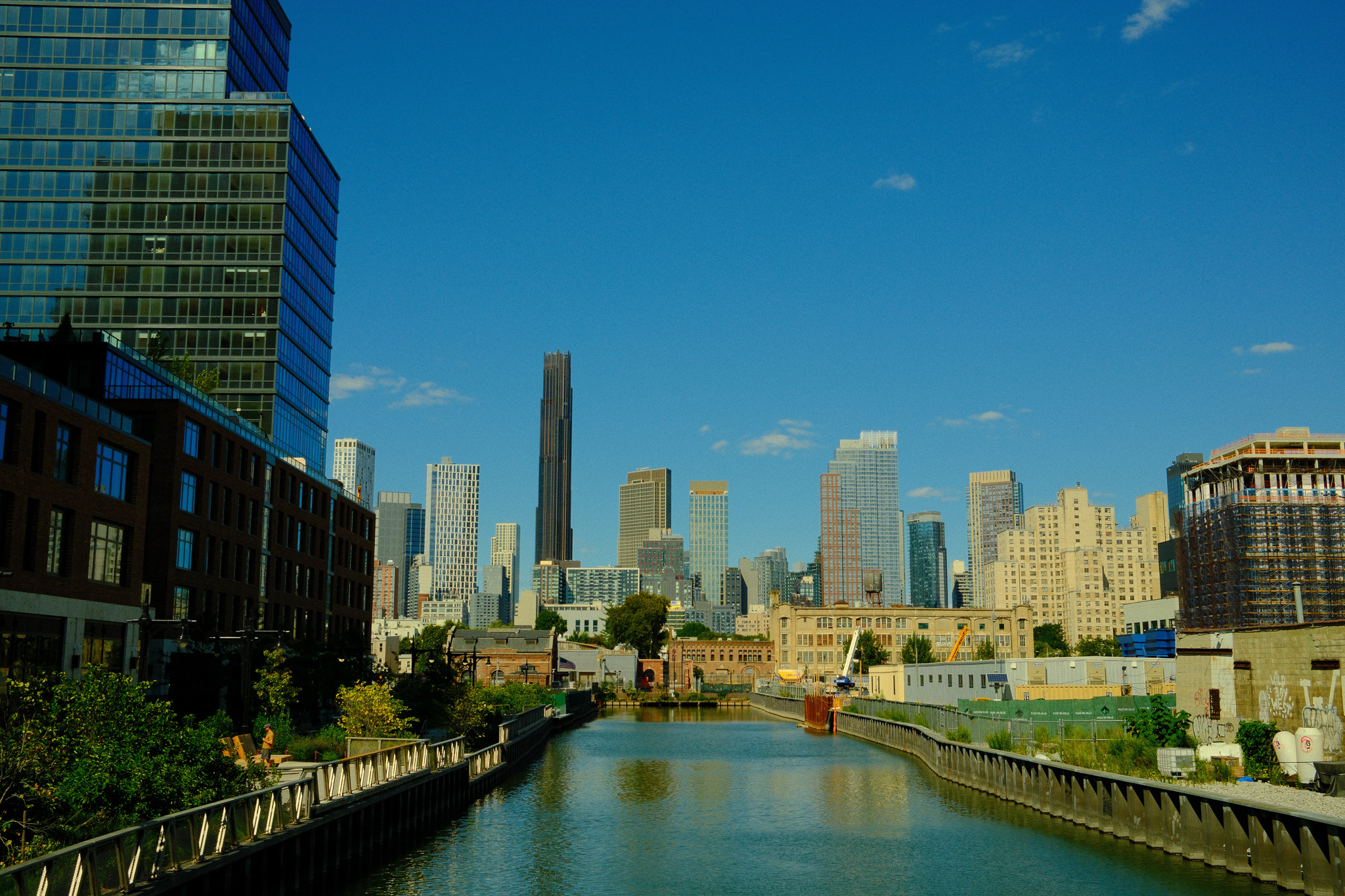 The Gowanus Canal surrounded by tall glass apartment buildings with skyscrapers in the distance.