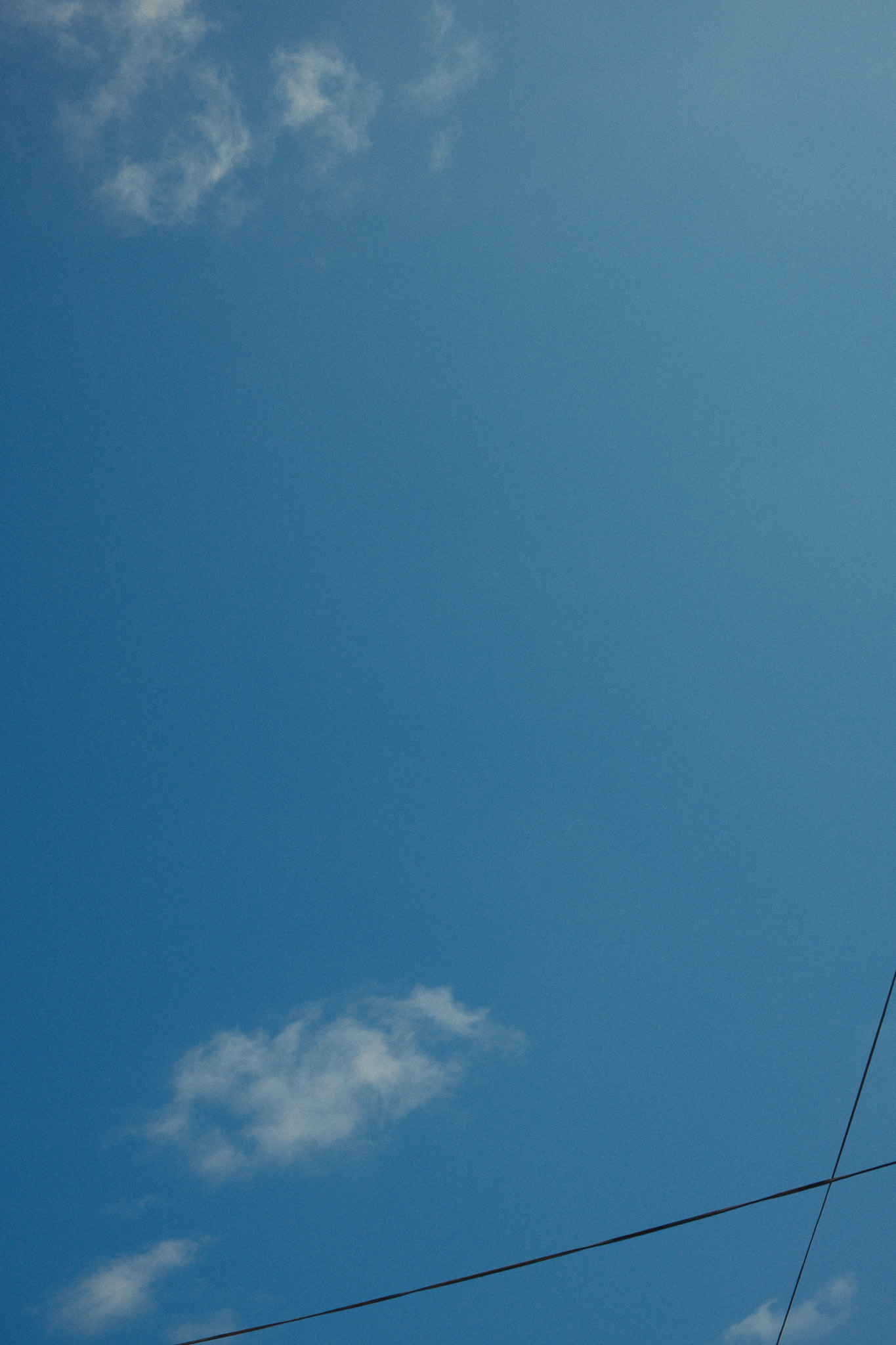 Summer sky crossed by overhead powerlines.