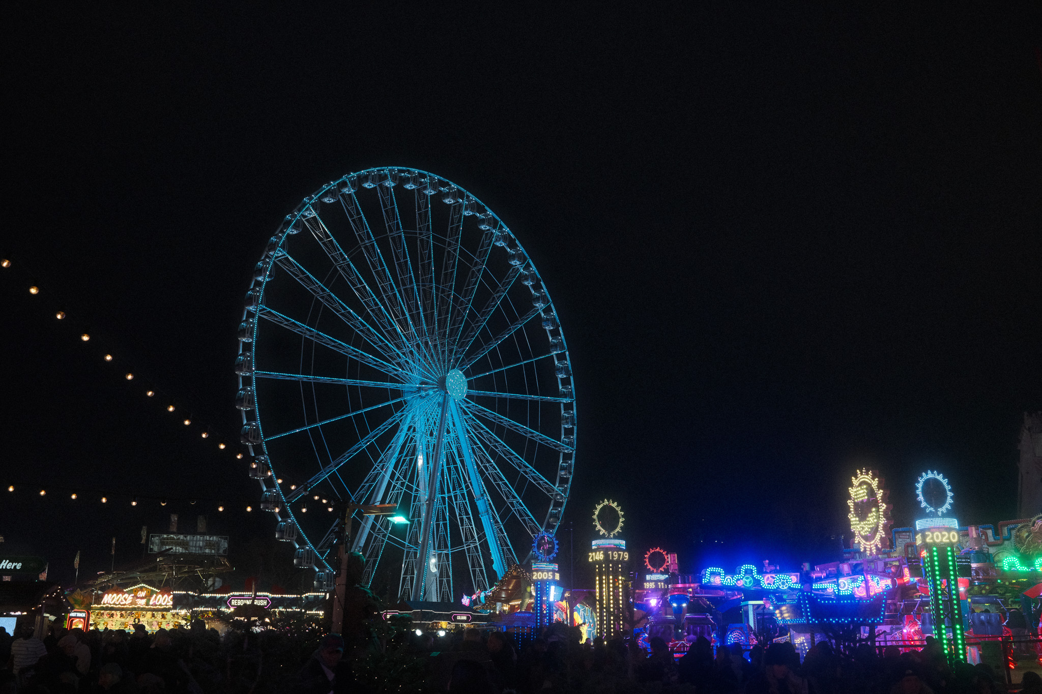 A large blue ferris wheel at night.