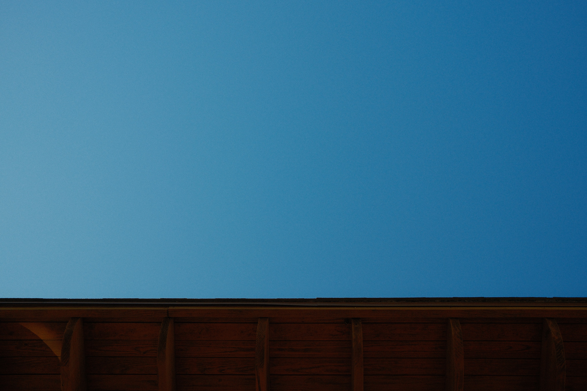 The underside of a roof with joists and the Texas sky.