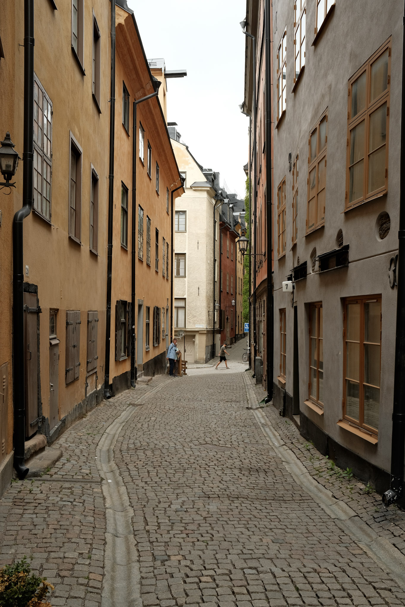 A thin cobblestone street in Gamla Stan, Stockholm. Old, 3-4 story buildings line the street with no setbacks.