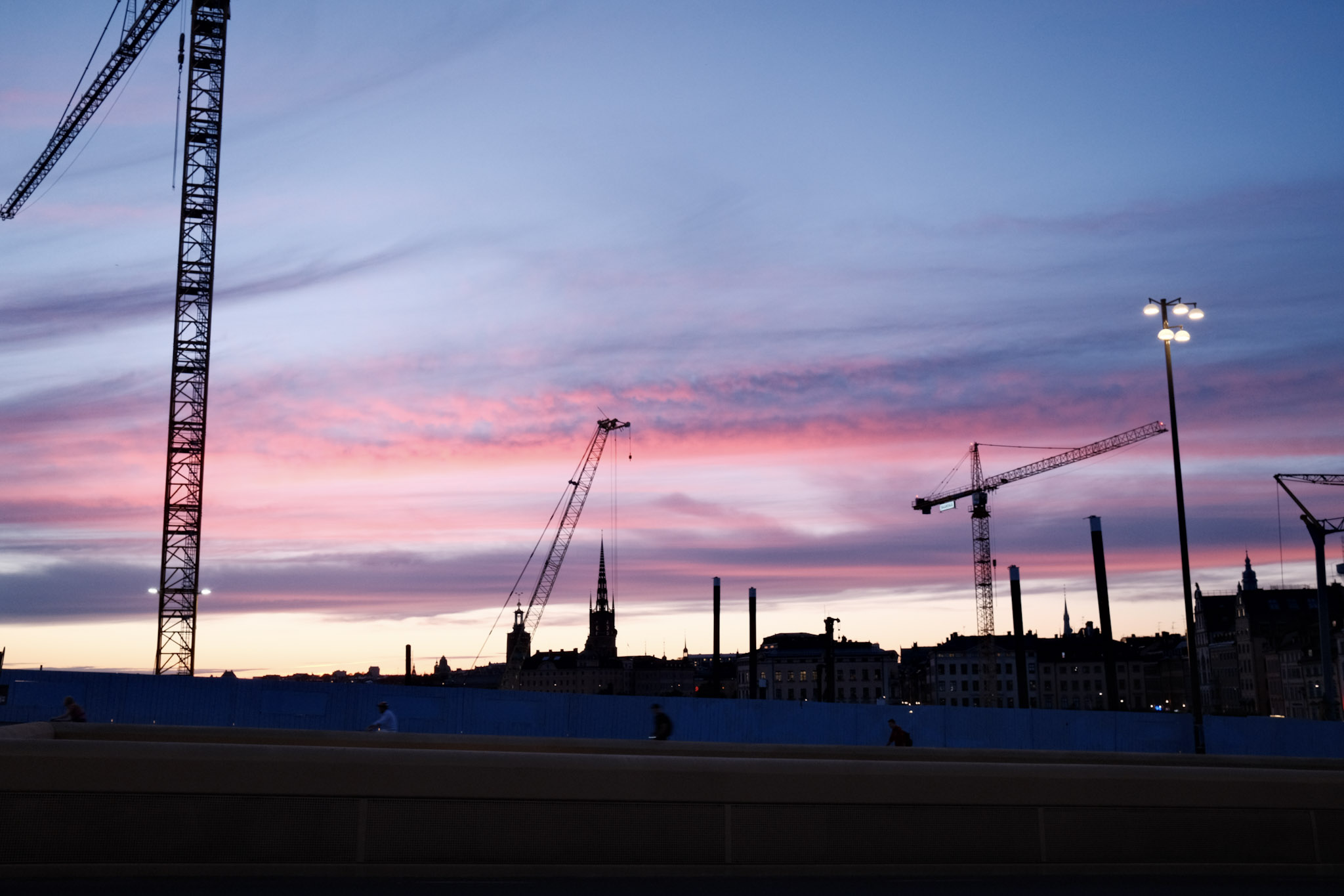 Twilight in Stockholm over a new construction pit with several cranes in the background