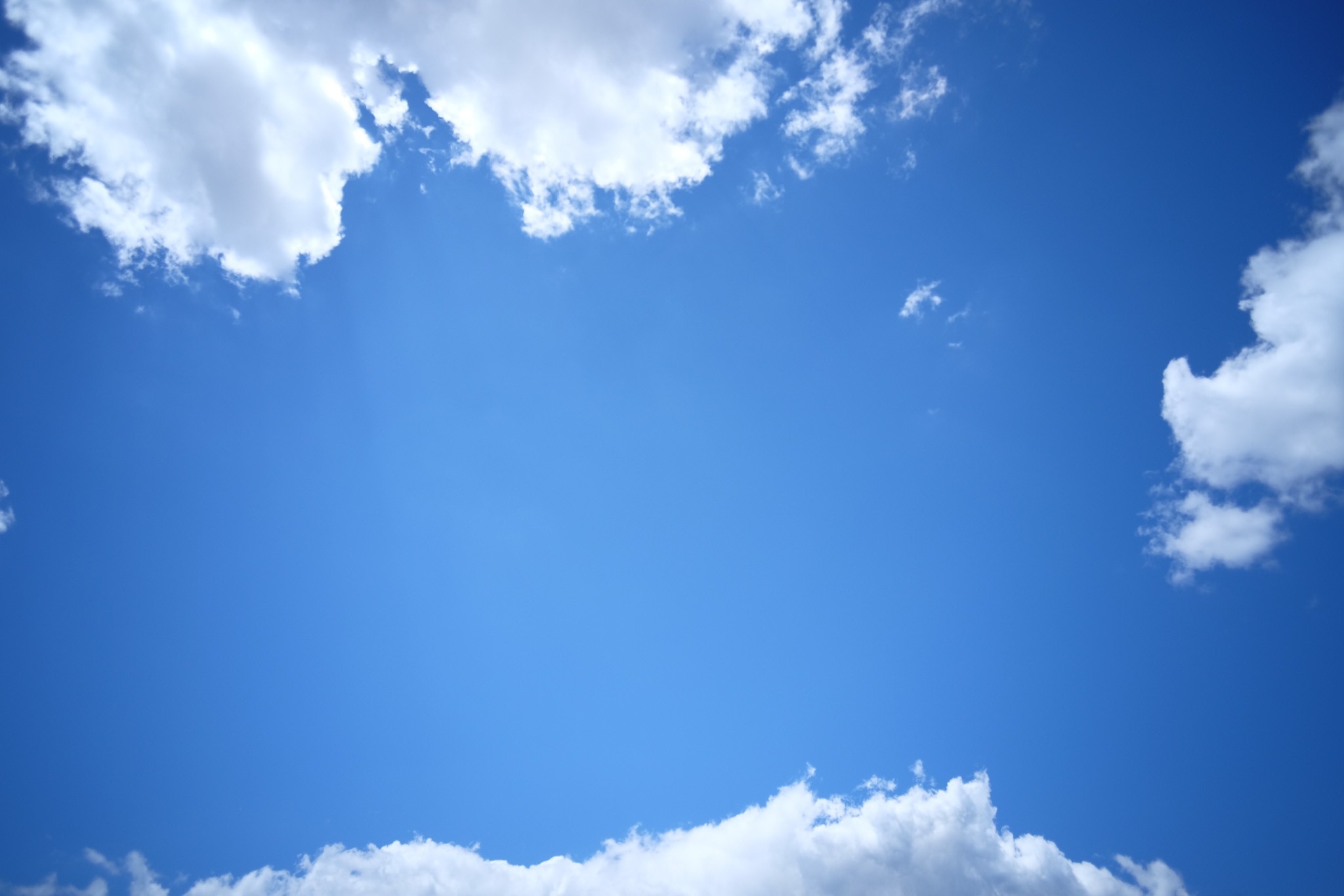 A blue sky looking up with a few low altitude clouds.