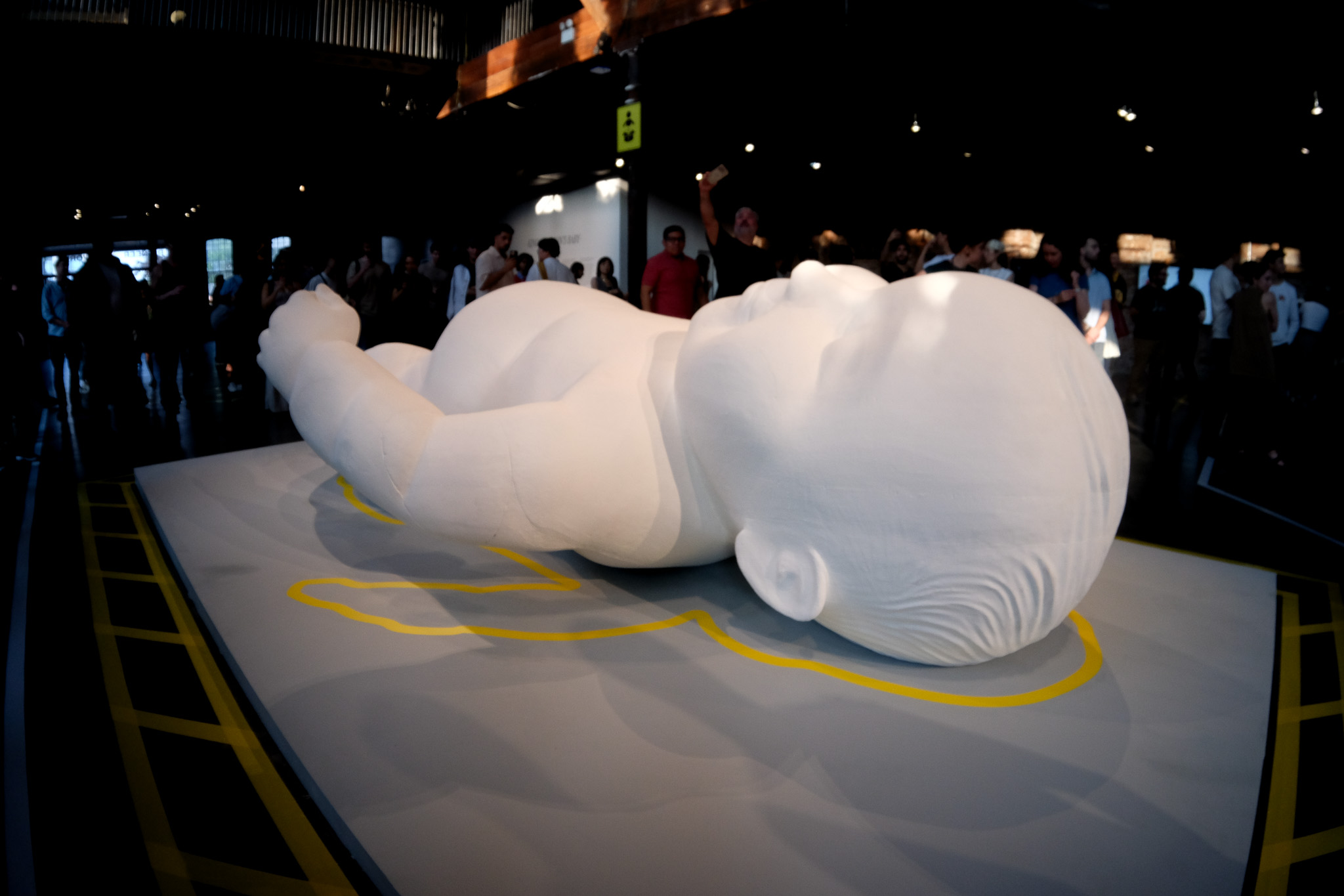 A giant white baby made out of foam in the middle of a grey platform.