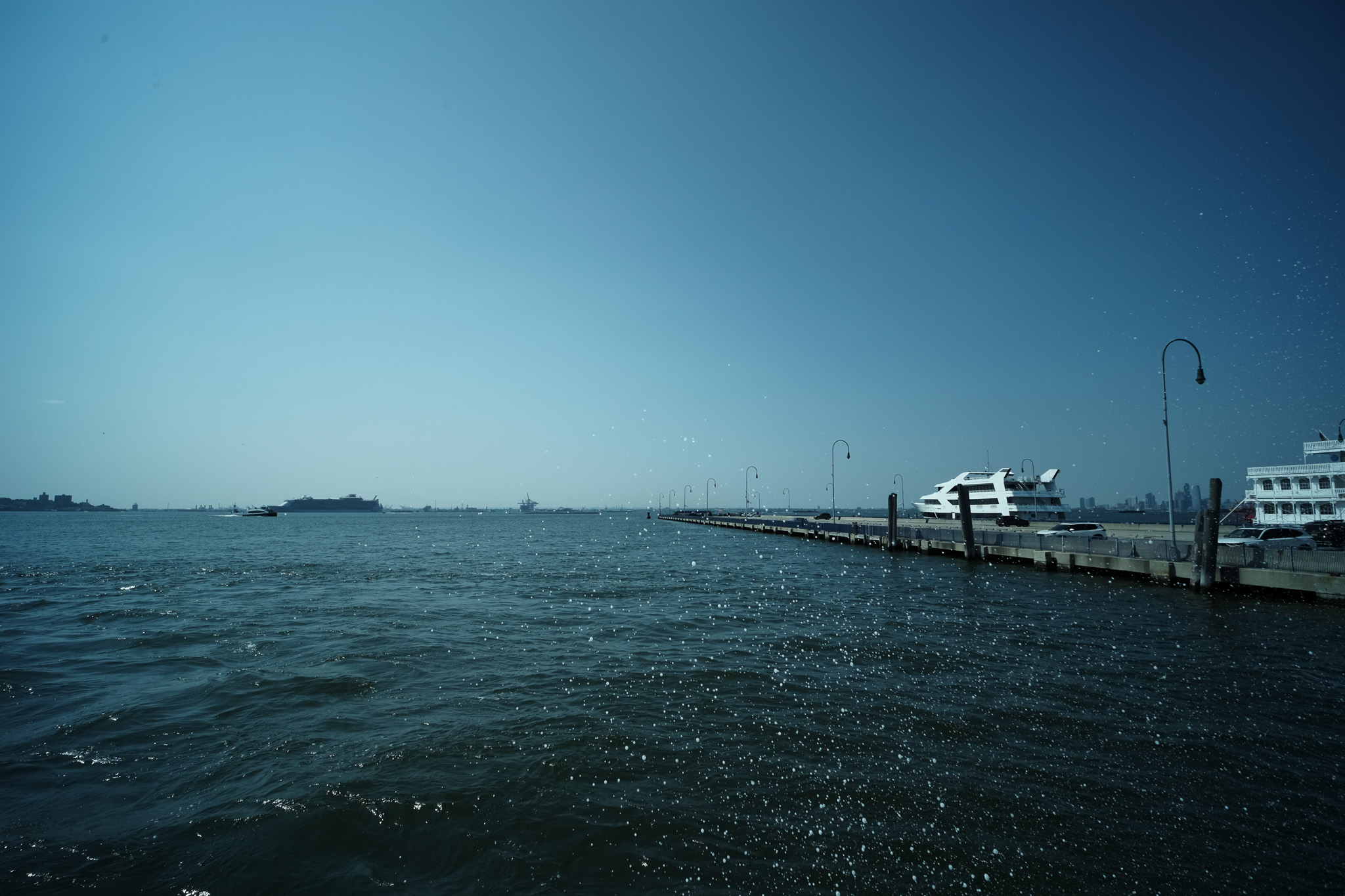 A splash of seafoam from a bay near a long concrete dock