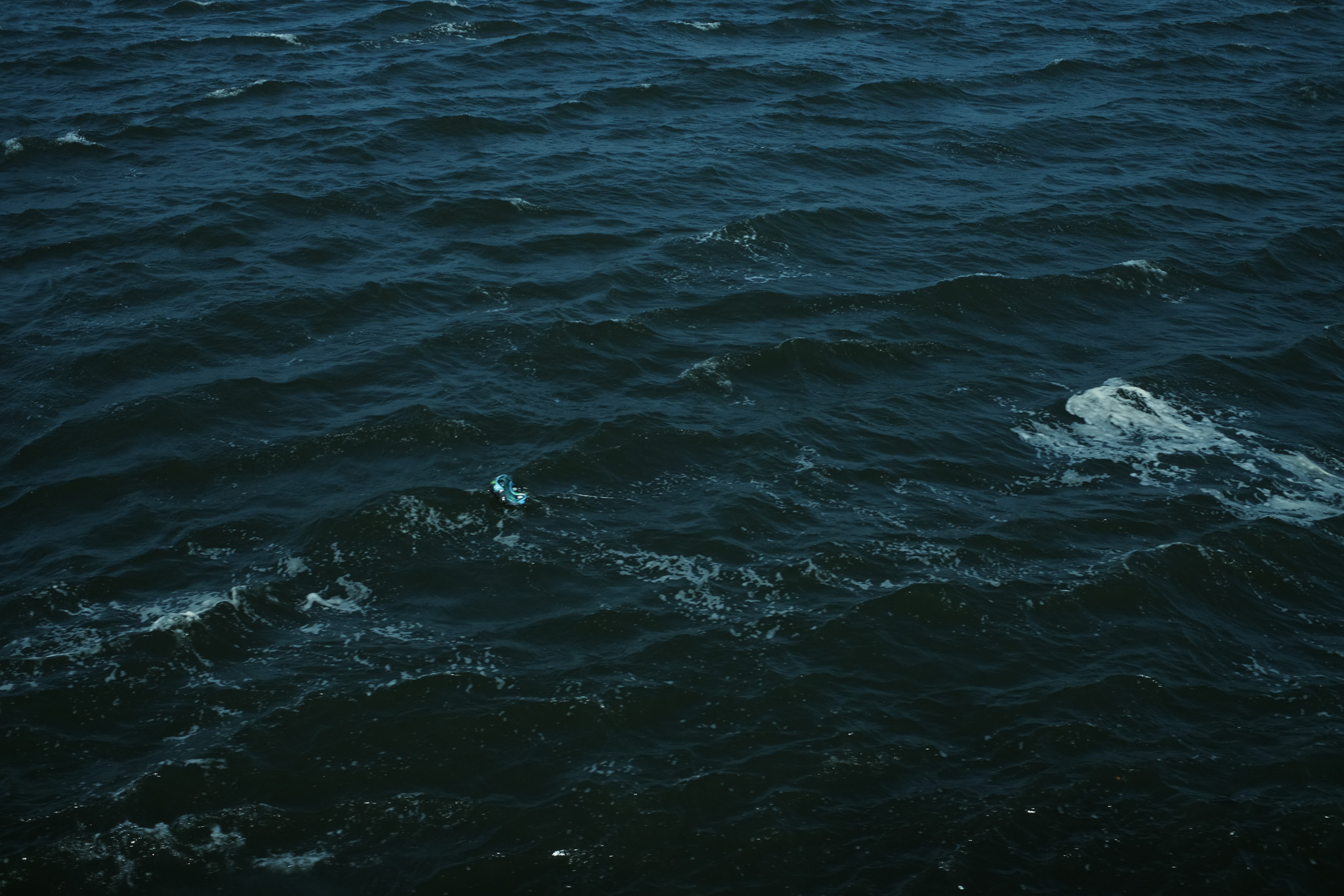 A photo of the waves with a trashed balloon floating in it.