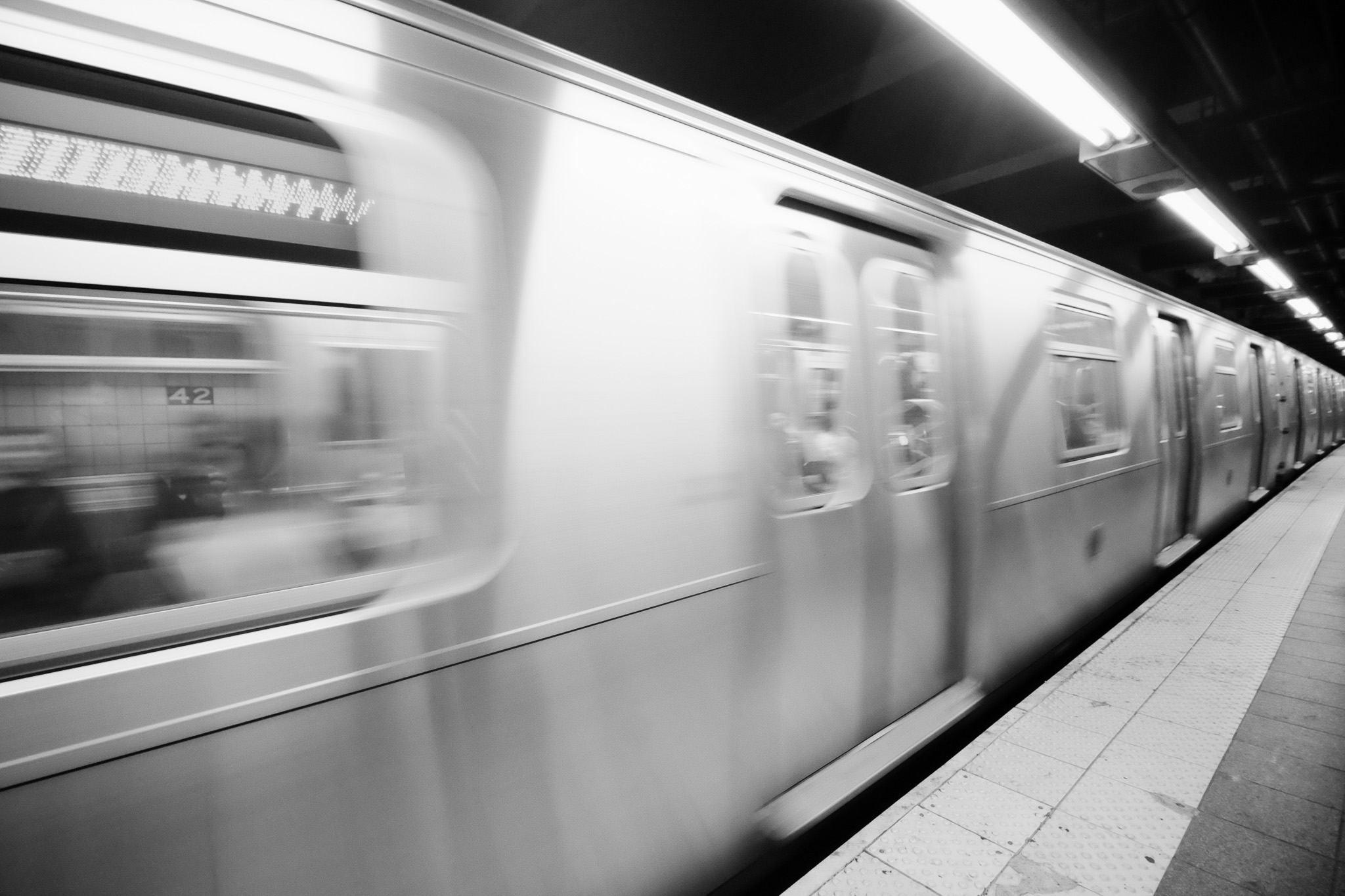 A train in motion pulling into Times Sq-42nd St station.