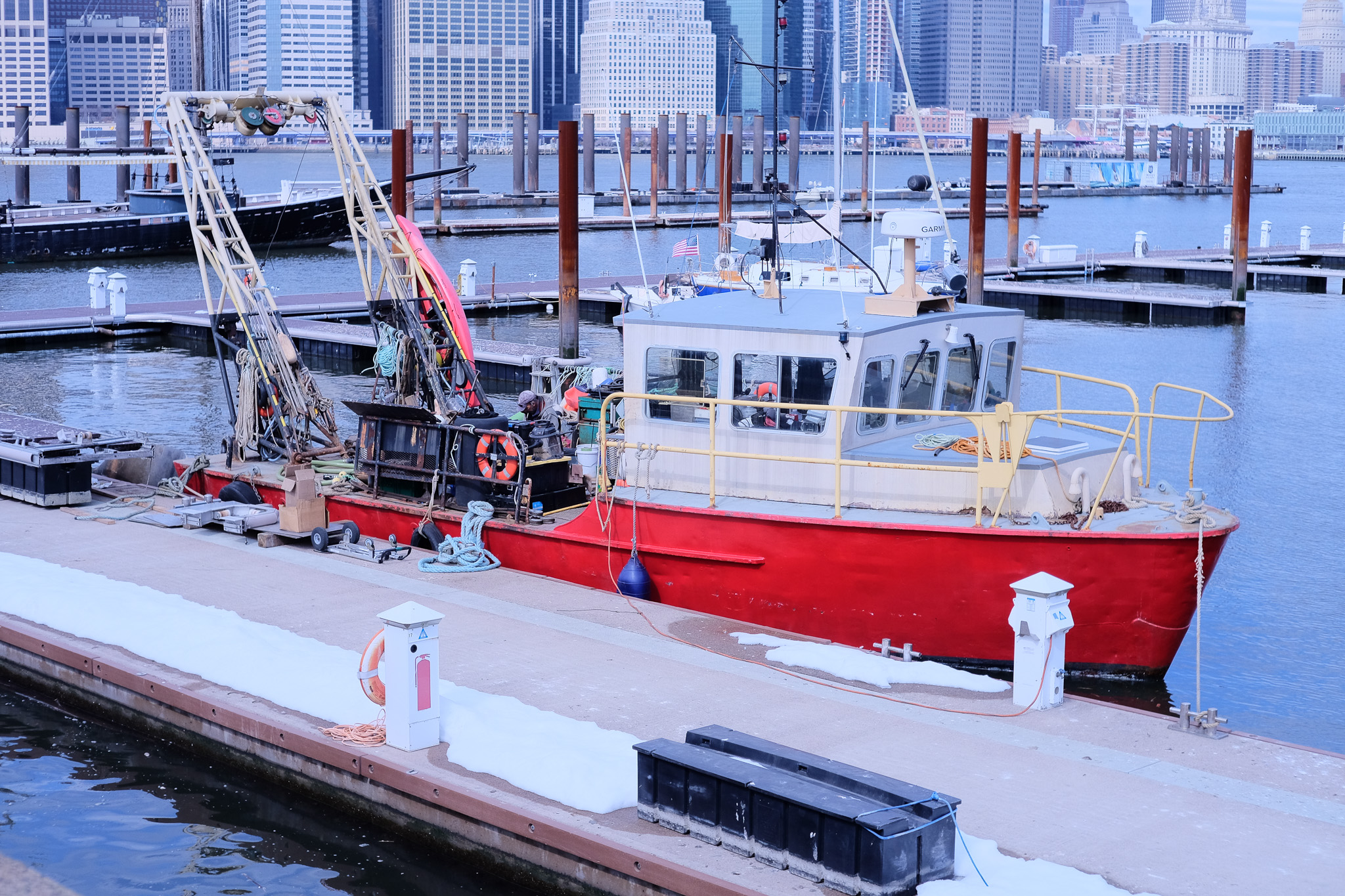 A small red workboat sitting docked in a marina slip.