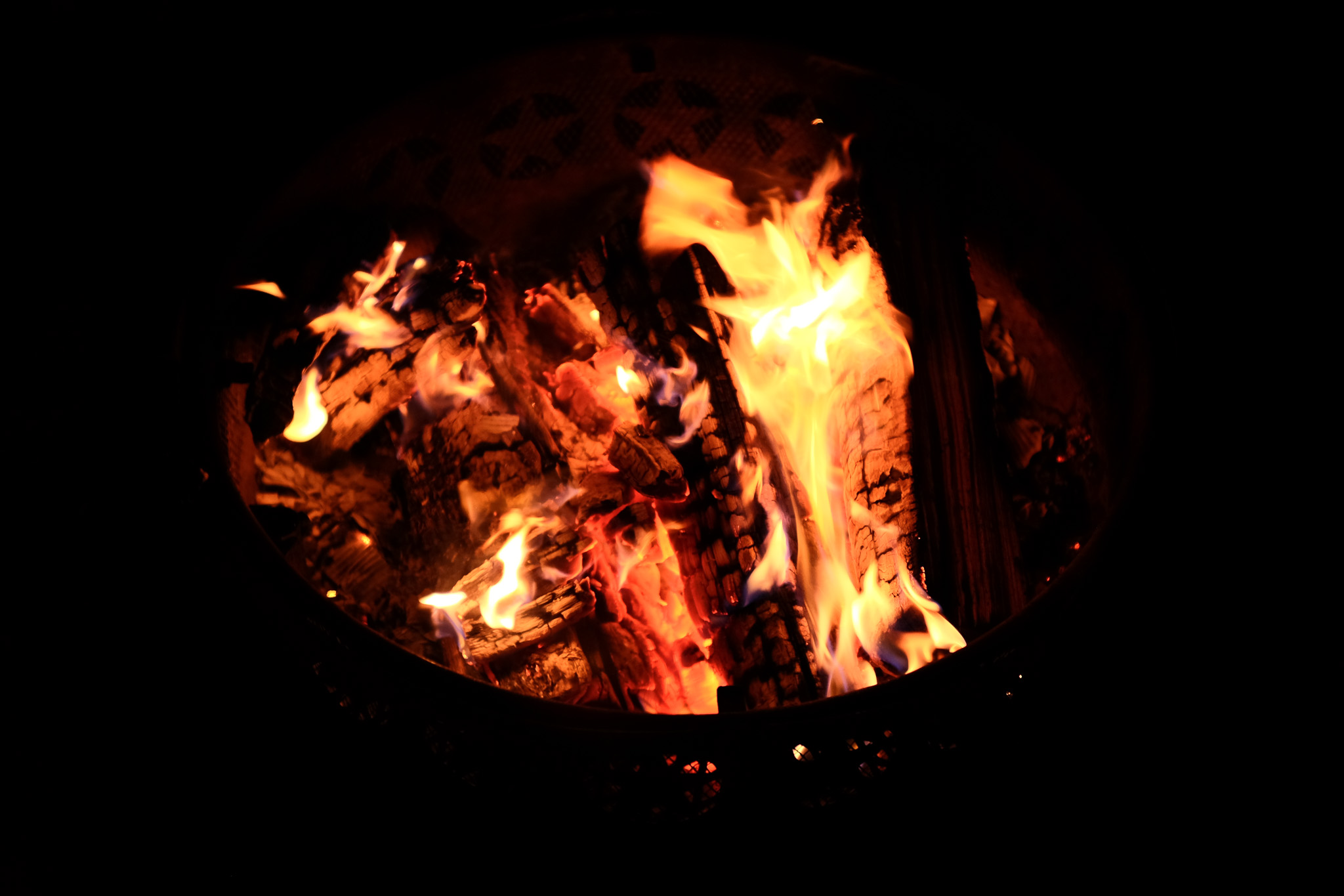 A metal fire pit full of a low burning fire