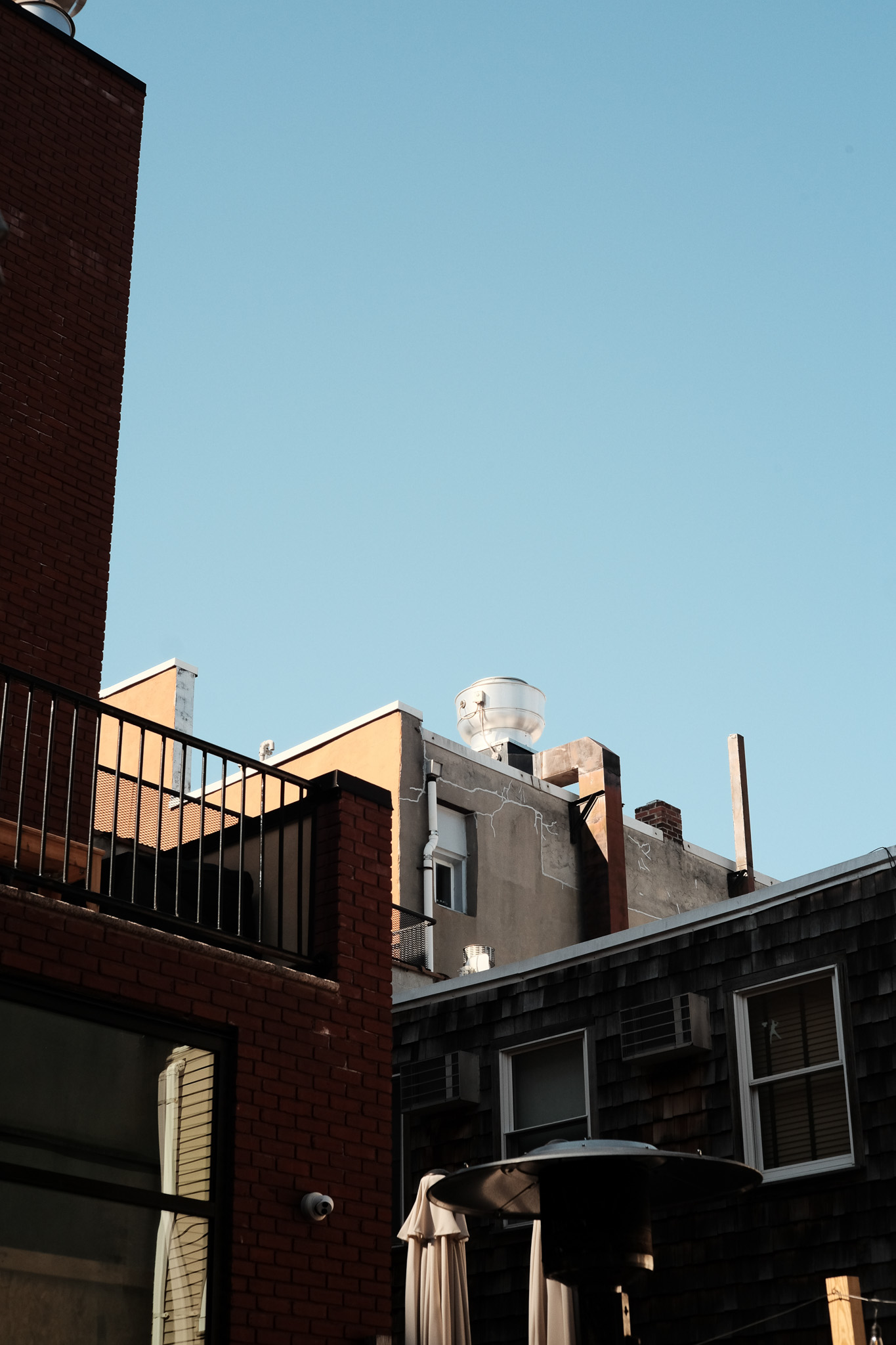 The corners of a few brick buildings topped by a exhaust unit