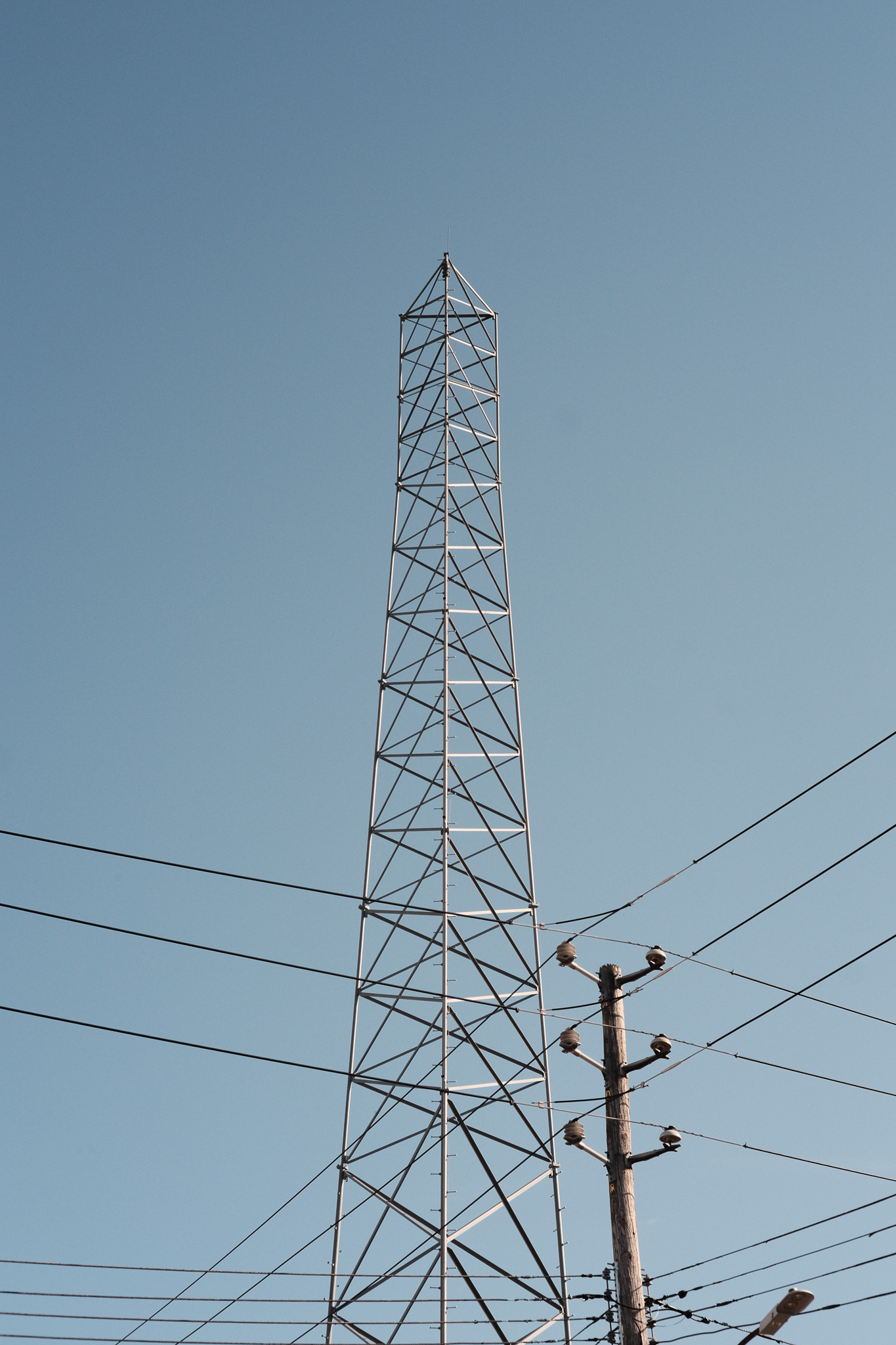 A former radio tower behind a utility pole and power lines.