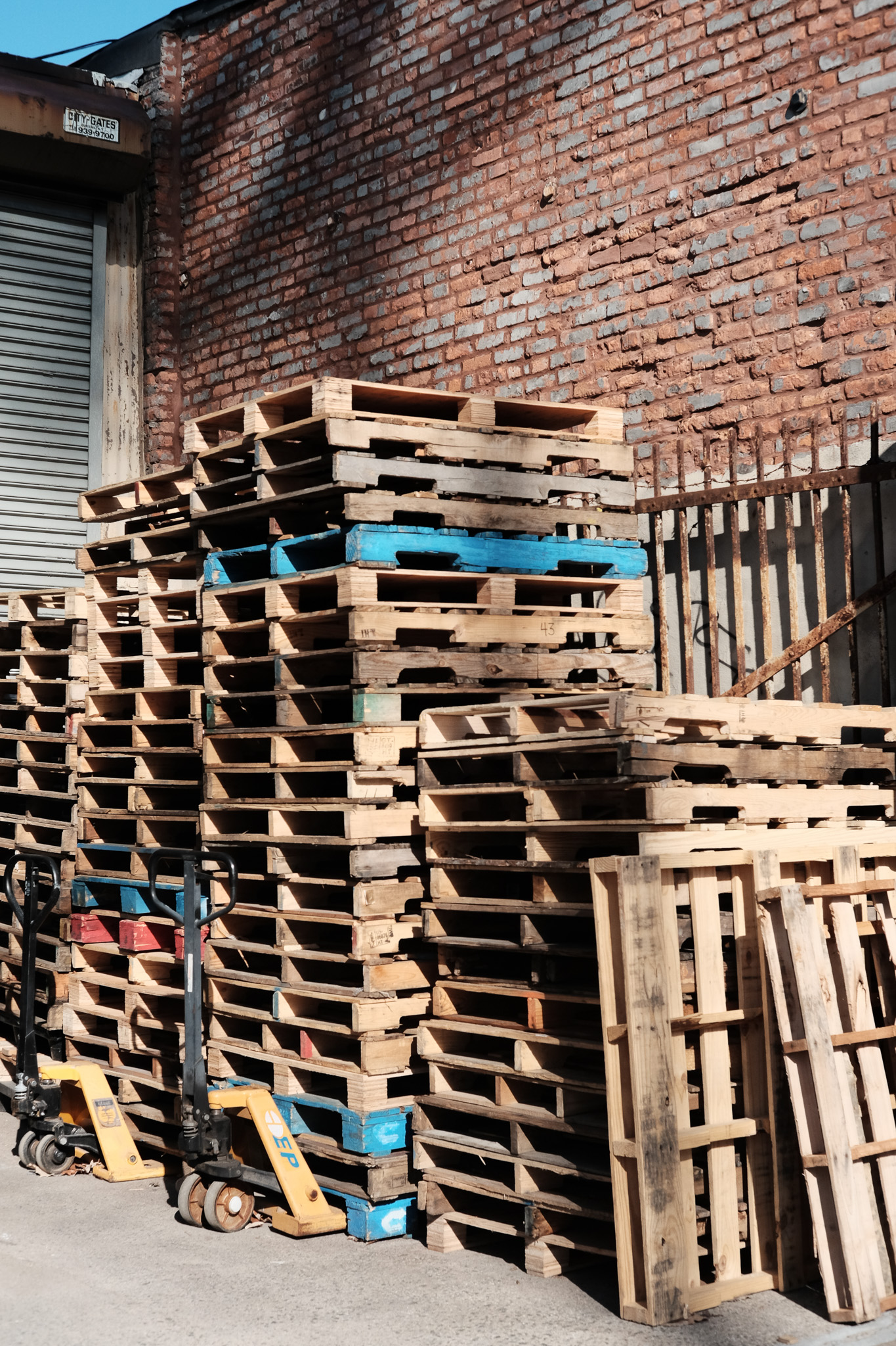 A bunch of stacked pallets in front of a brick wall