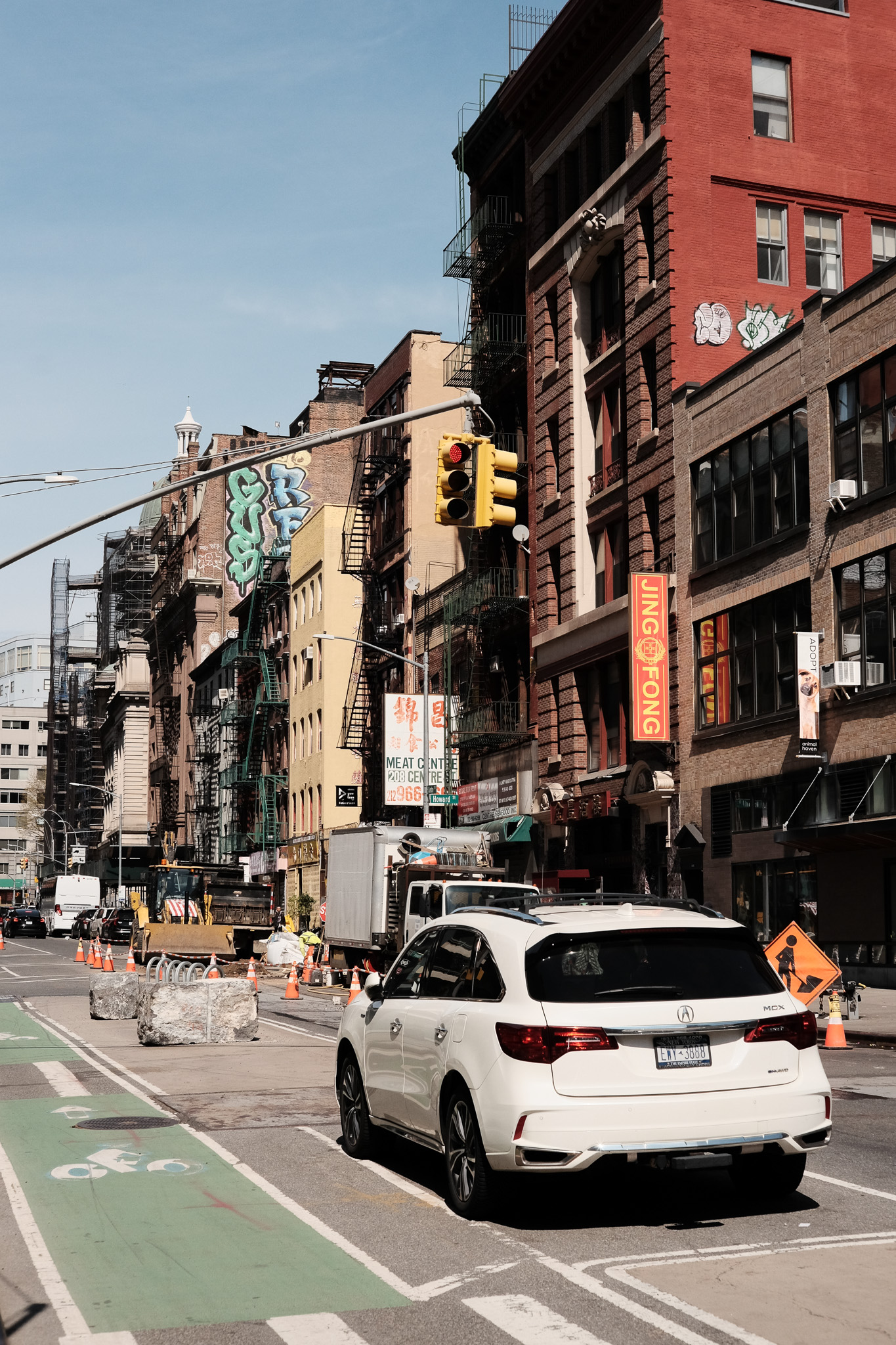 A Manhattan street in chinatown with a bike lane and lots of construction